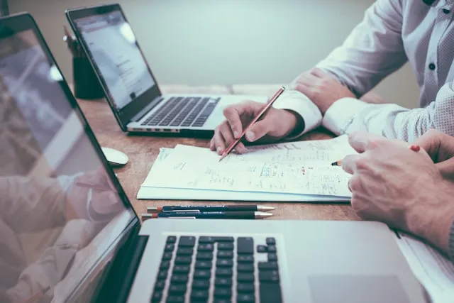 Grupo de pessoas sentadas ao redor de uma mesa com notebooks